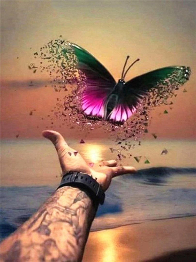 Diamond paint af sommerfugl, der opløses og sendes mod himlen ude ved strandkanten.