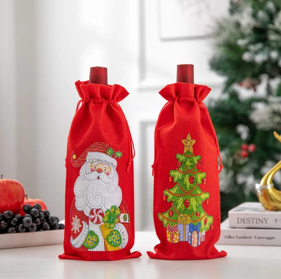 2 røde flaskeskjulere med diamond paint. Motiv af overrasket julemand med røde kinder og gave i hånden.
Og motiv af juletræ med pakker under.
