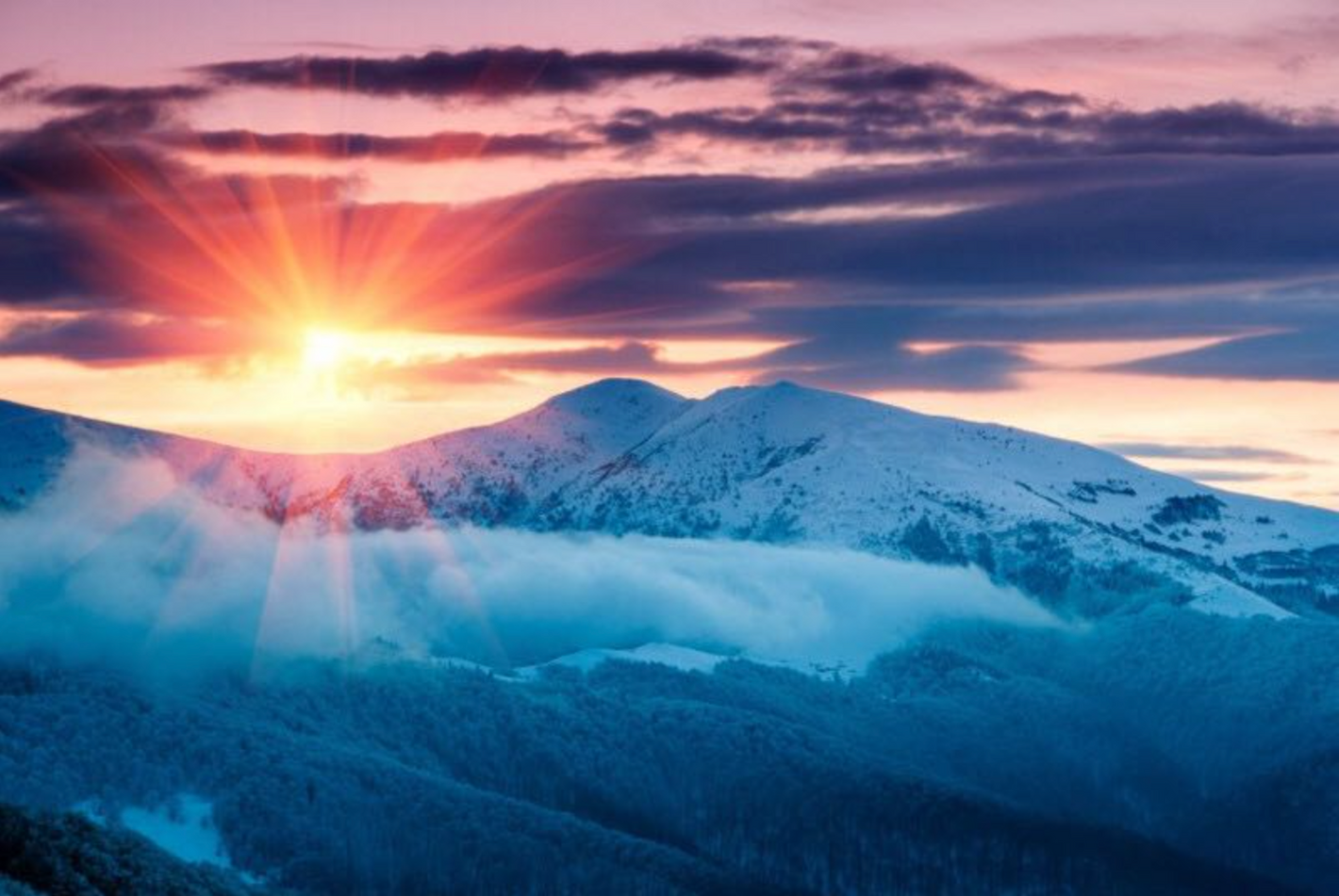 Solopgang over sneklædte bjerge