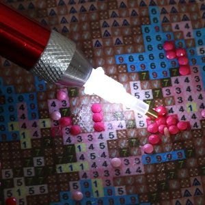 Rød pen til diamond paint. 
Der er lys i tippen, der lyser lærredet op.