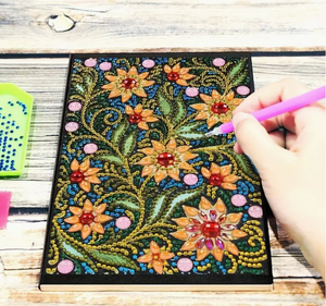 Diamond painting notesbog dekoreret med diamanter. Motivet er gule og røde blomster.