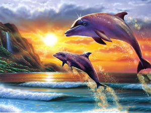 Diamond painting af springende delfiner med solnedgang over bjerge i baggrunden