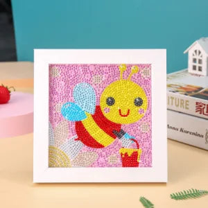 Diamond painting billede med lille bi på lyserød baggrund i hvid ramme.