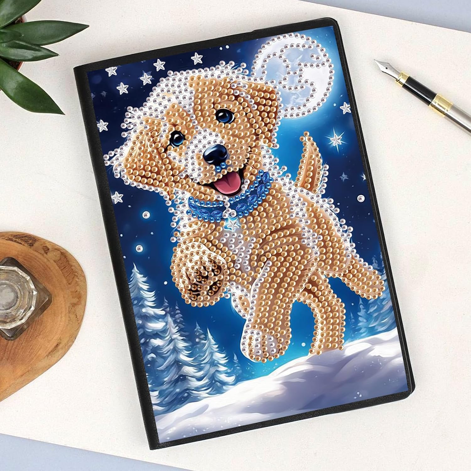 Diamond painting notesbog med en glad hund i spring. Omgivet af sne og måneskin.