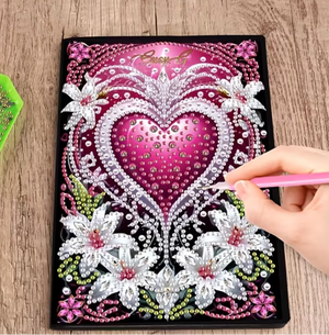 Diamond painting notesbog med pink hjerte omgivet af hvide blomster.