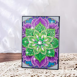 Diamond art notesbog med mandalamønster i grønne, lilla og blå nuancer.