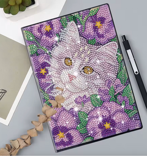 Diamond paint notesbog med en kat omgivet af lilla blomster.