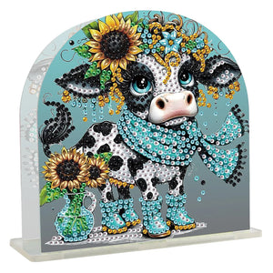 Diamond paint servietholder med en broget ko med blåt tørklæde og støvler. Solsikker og perler.