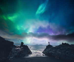 Diamond painting af nordlys mellem klipper over havet.